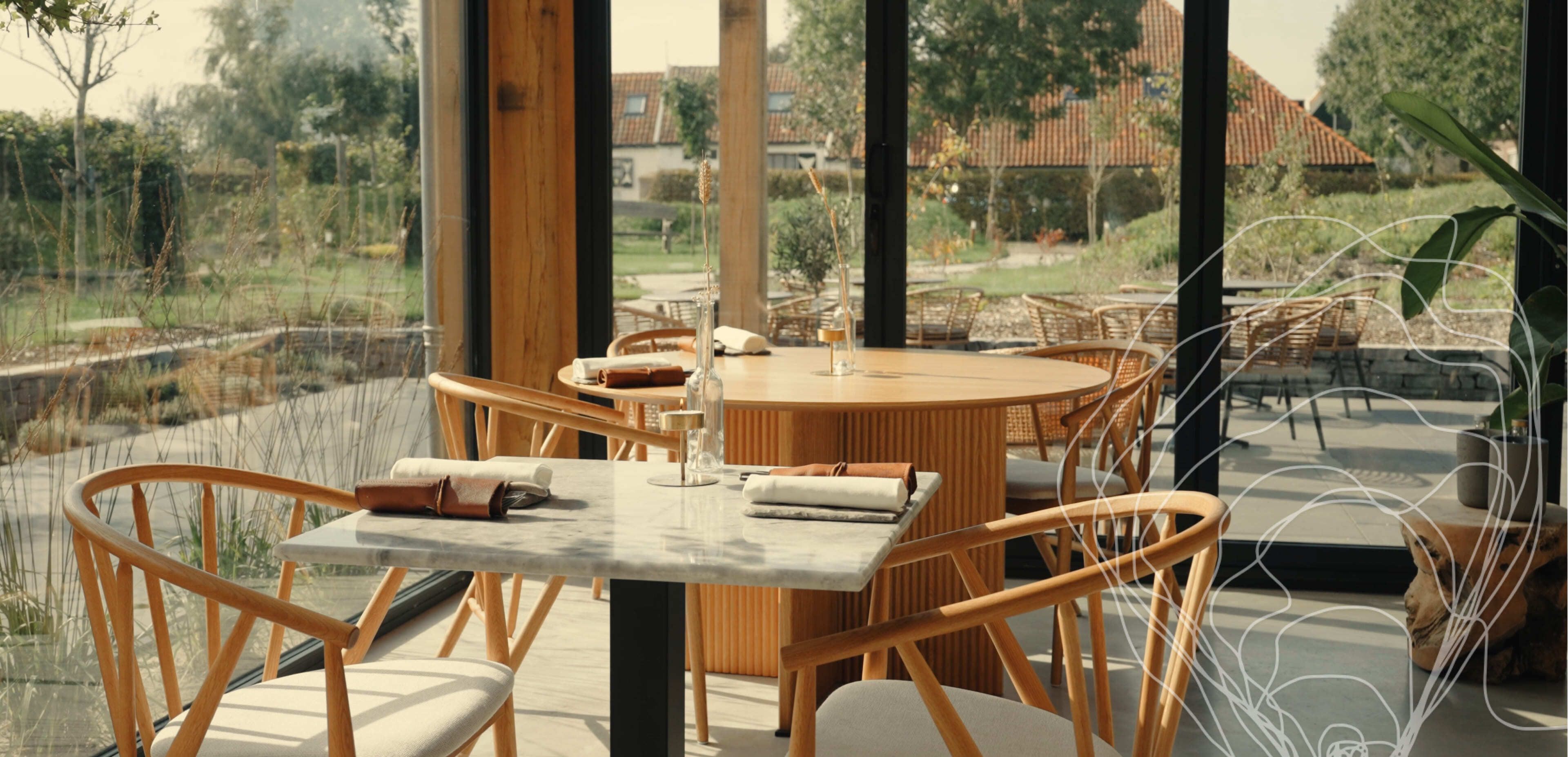 Een zonnig restaurantgedeelte met houten stoelen, marmer en houten tafels, grote ramen met uitzicht op een groene tuin. Ideaal voor het houden van vergaderingen over webshops of het ontwerpen van mooie websites.